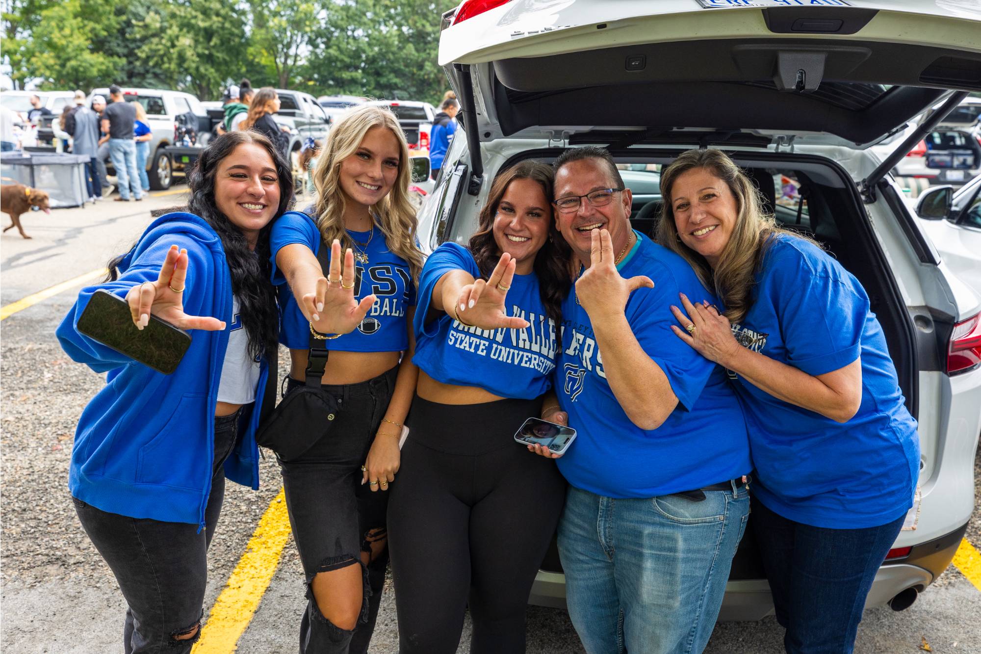 A Laker family smiling at the camera at a football game tailgate